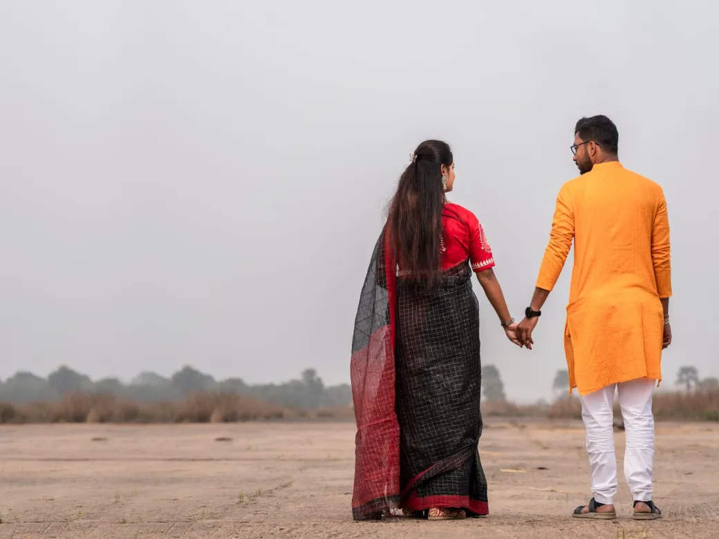 A married couple walking hand in hand, seen from behind