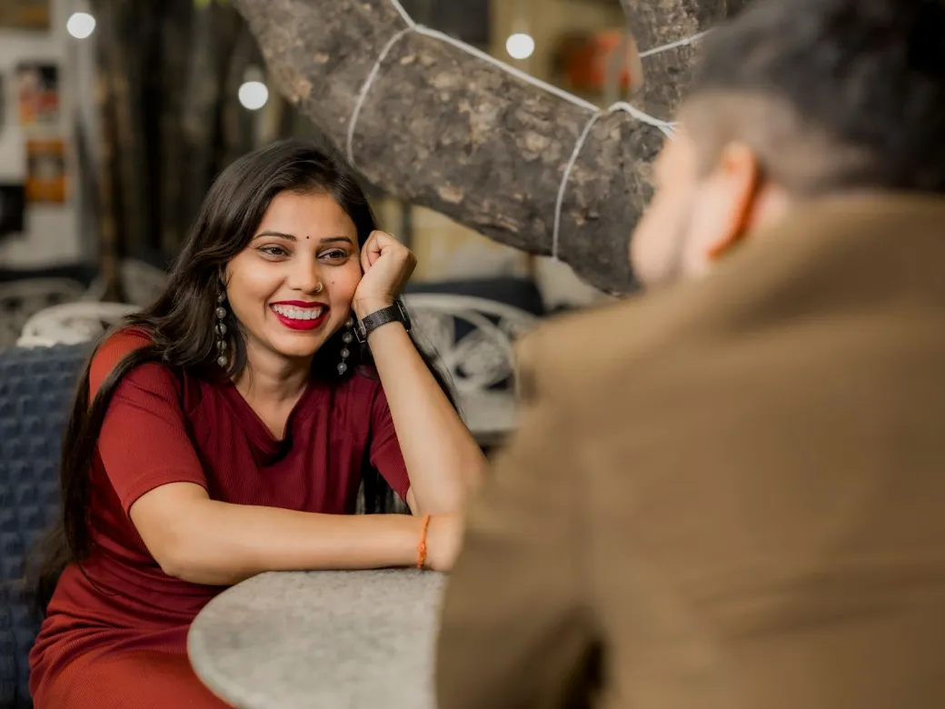 A young couple smiling and talking at a cafe