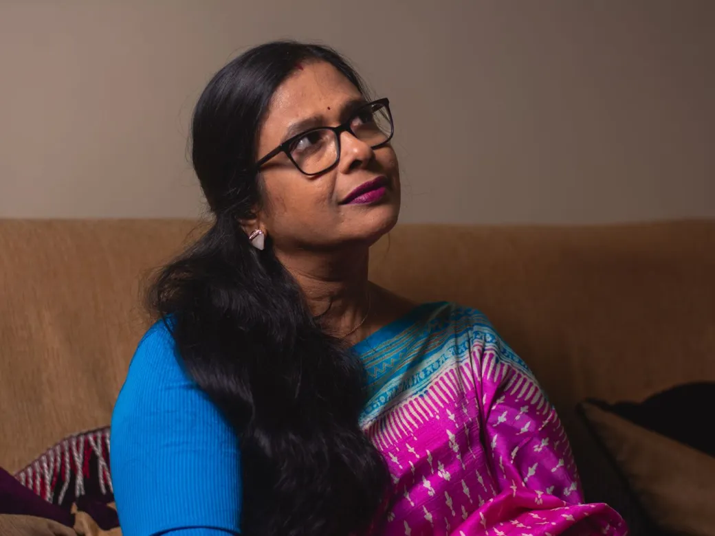 A woman in a saree sitting quietly at home, deep in thought